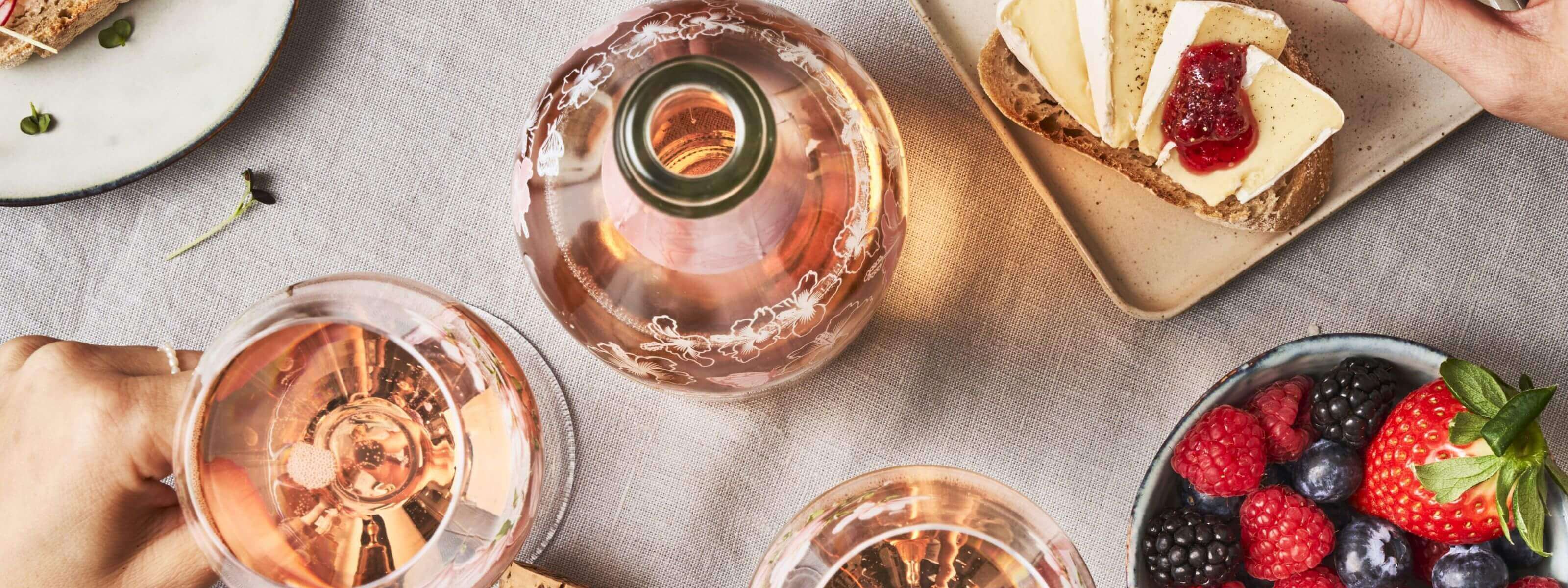 Am gedeckten Tisch mit Brötchen und Beeren steht eine Flsche Schlumberger Spring Edition und zwei Gläser