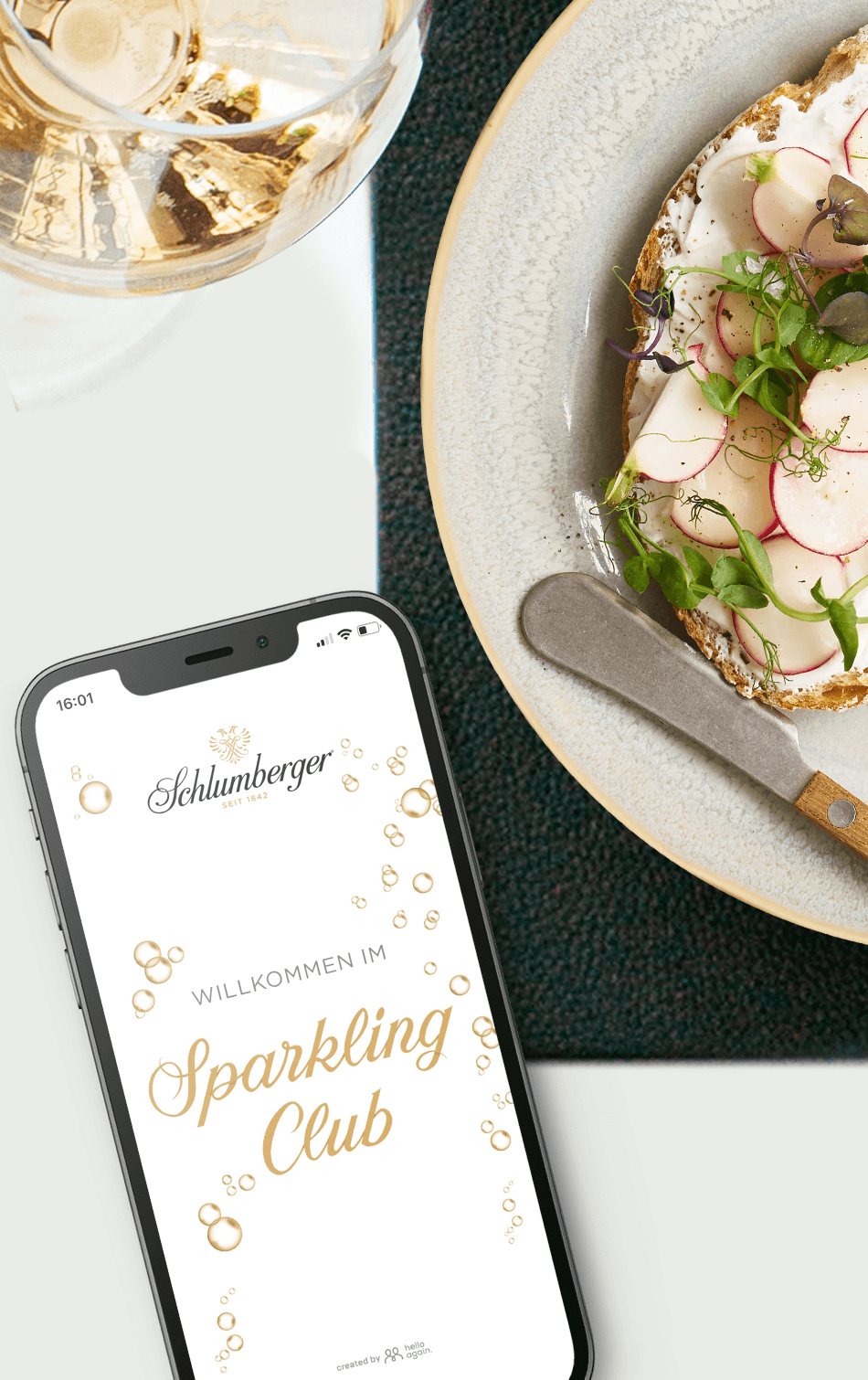 Schlumberger Sektglas und Handy mit Sparkling Club App auf einen gedeckten Esstisch 