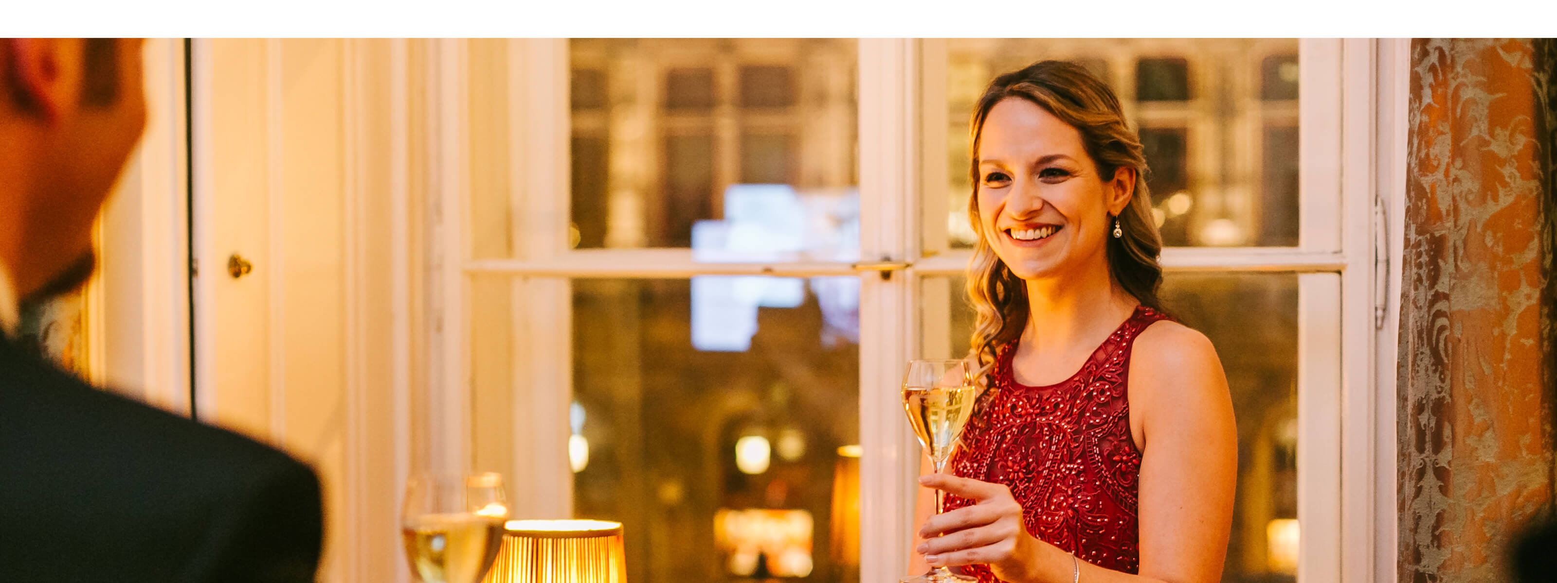 Dame im roten Kleid erwartet mit Sektglas in der Hand einen Mann