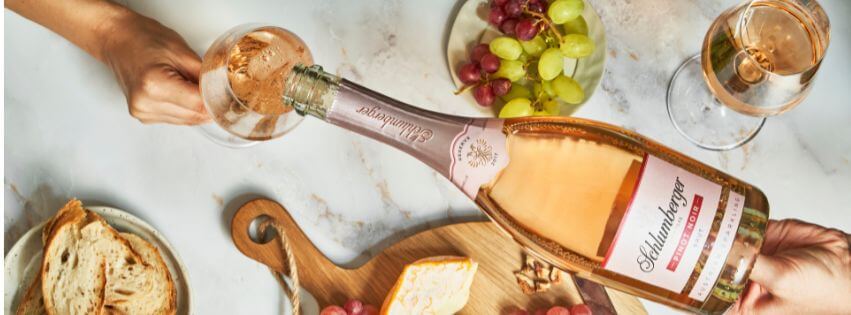 Pinot Noir Reserve wird in ein Glas einschenkt, daneben steht eine Käseplatte und Trauben