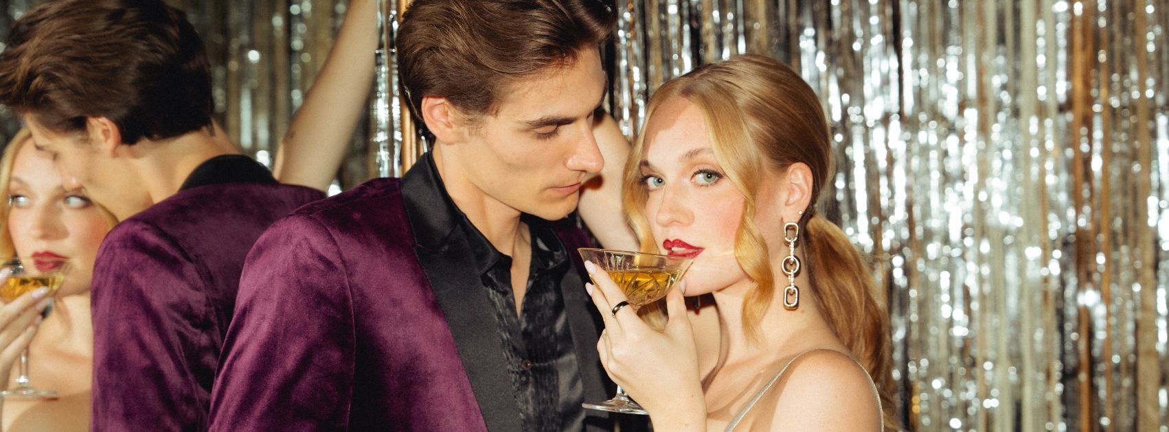 Mann und Frau stehen eng bei einander, Dame trinkt aus einer Sektschale