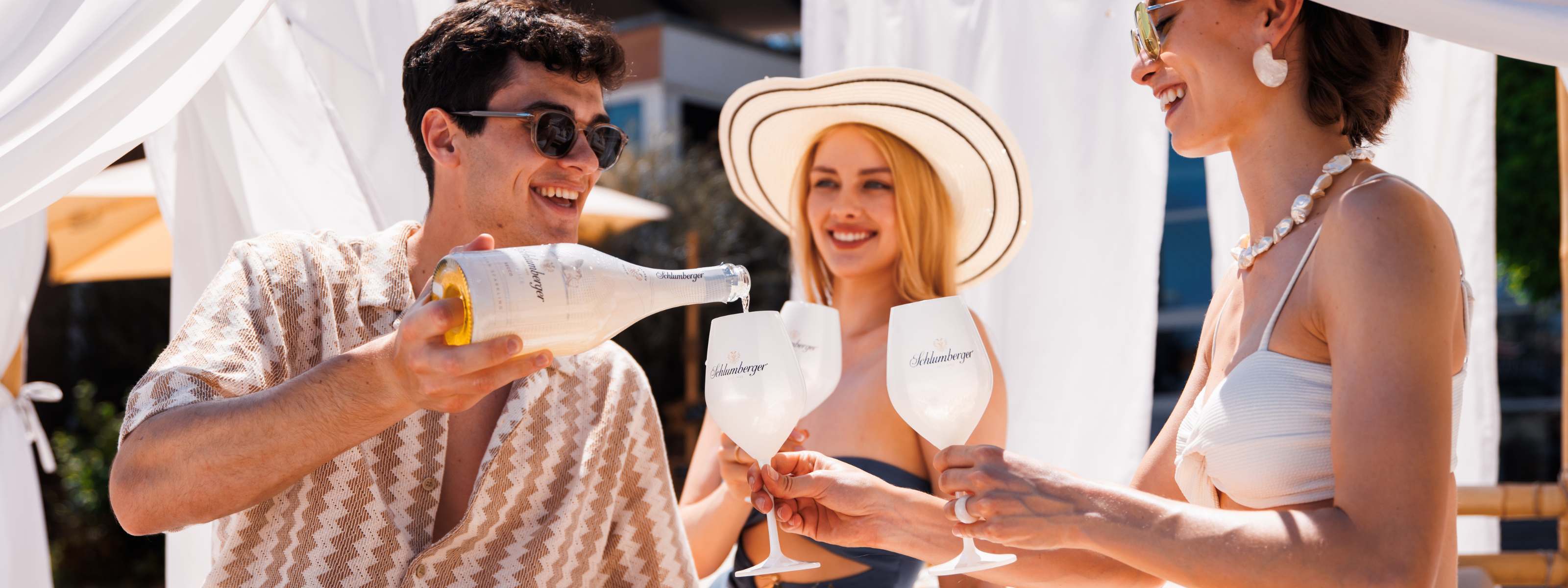 Ein Mann schenkt zwei Damen White Ice Secco ein