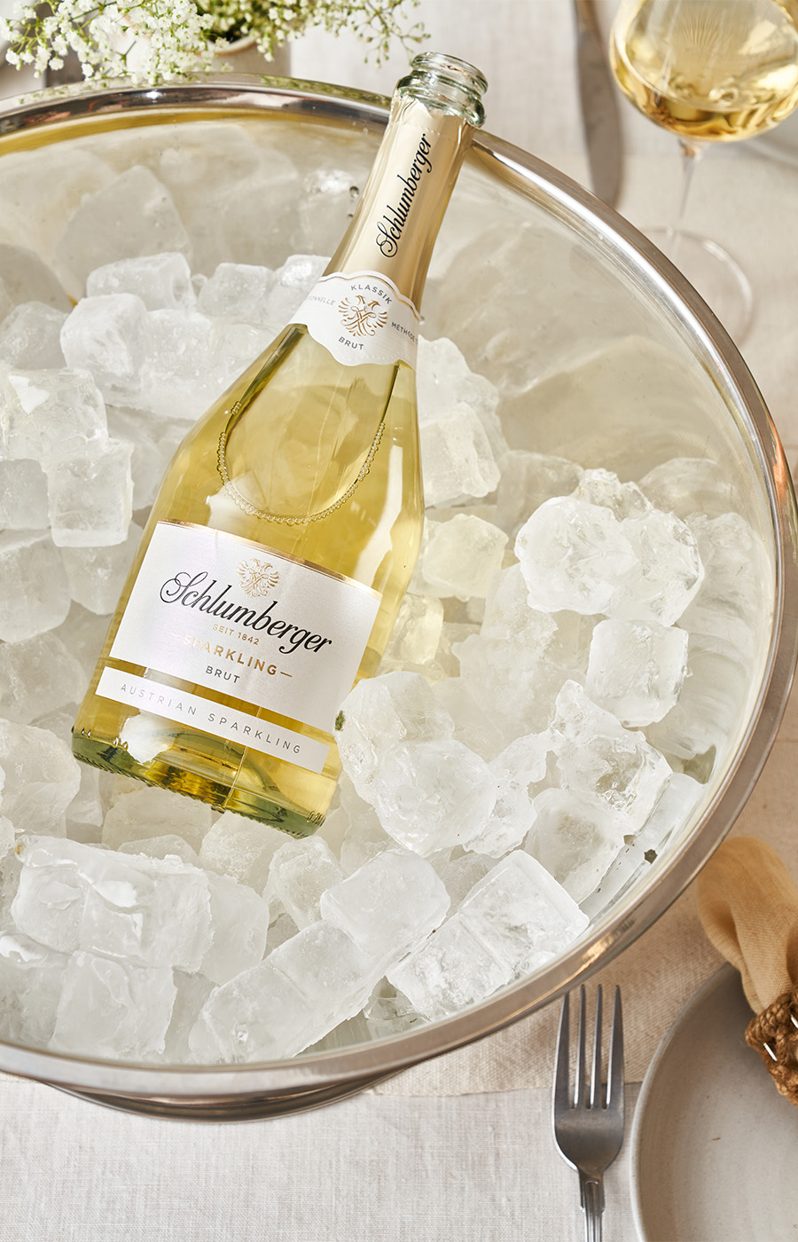 Eine Flasche Schlumberger Sparkling in einem Sektkühler auf gedecktem Tisch.