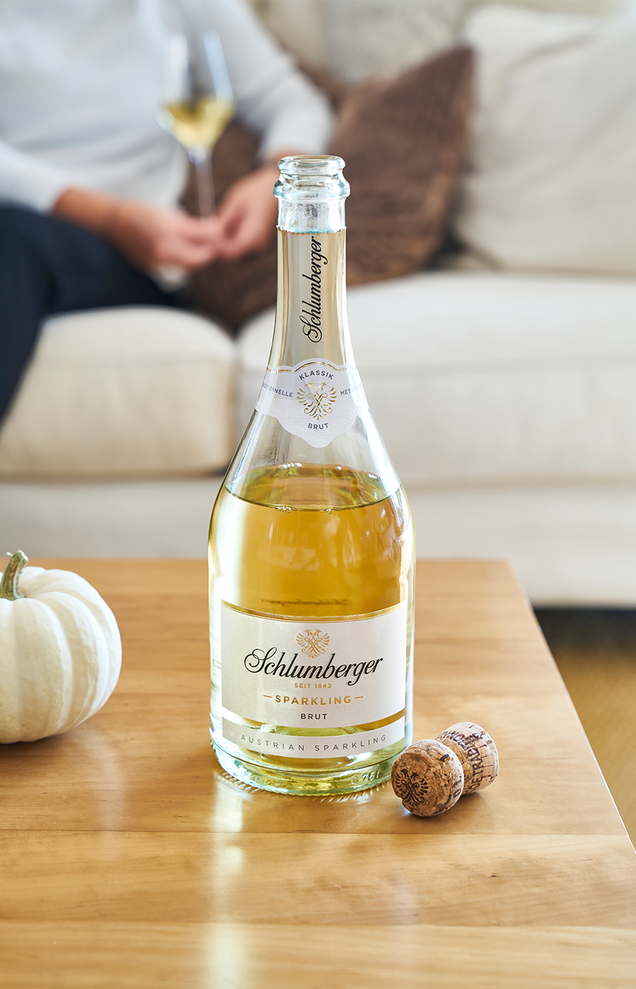 Eine geöffnete Schlumberger Sparkling Flasche steht auf einem Tisch mit dem Korken und einem Kürbis daneben.