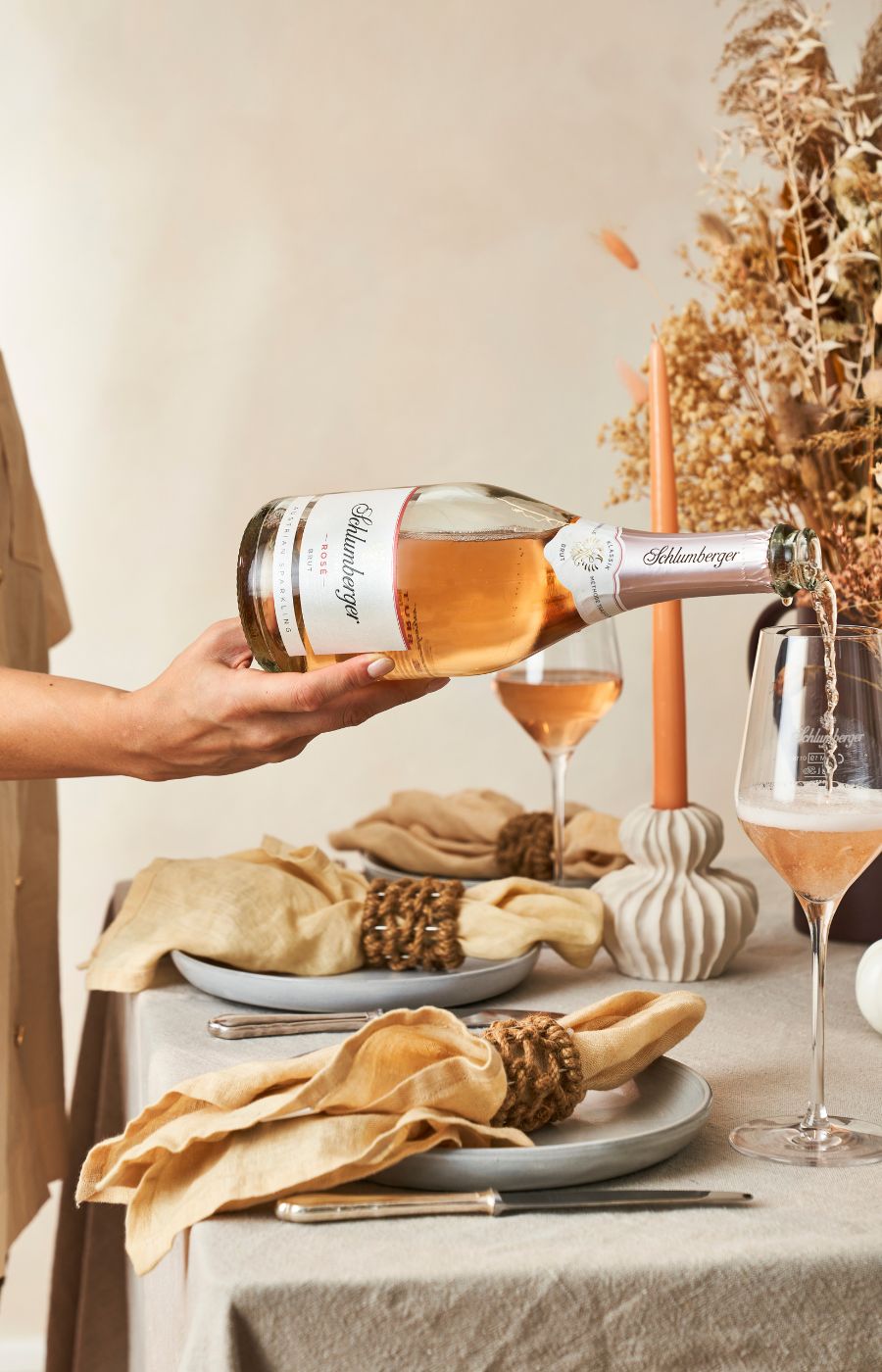 Dame schenkt Rose Brut in Gläsern am gedeckten Tisch ein