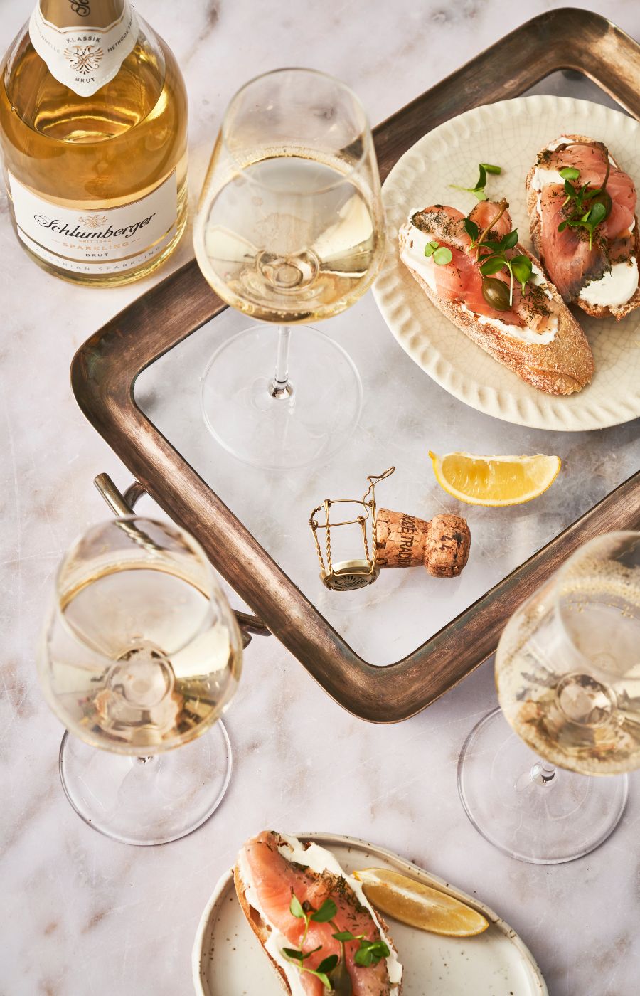 Schlumberger Sparkling mit 3 Gläsern und Lachsbrötchen stehen auf einem Tisch mit Tablett