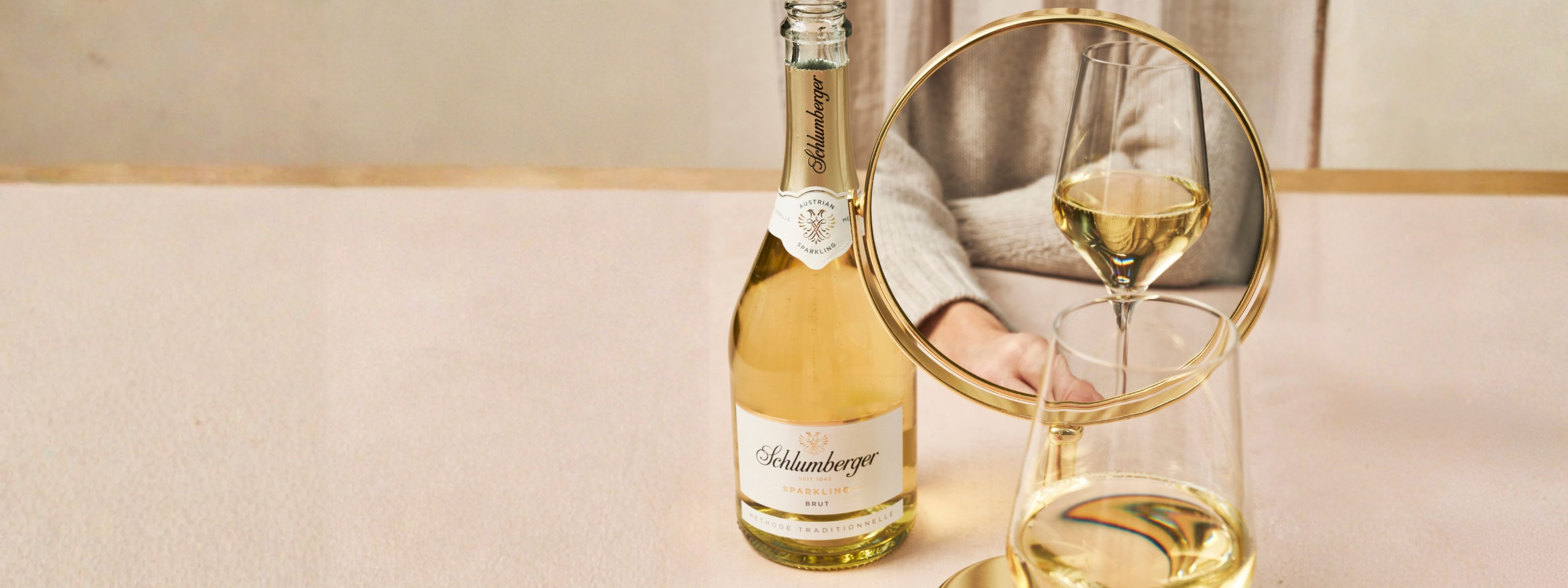 Dame sitzt vor Spiegel mit einer Flasche Sparkling und einem Glas