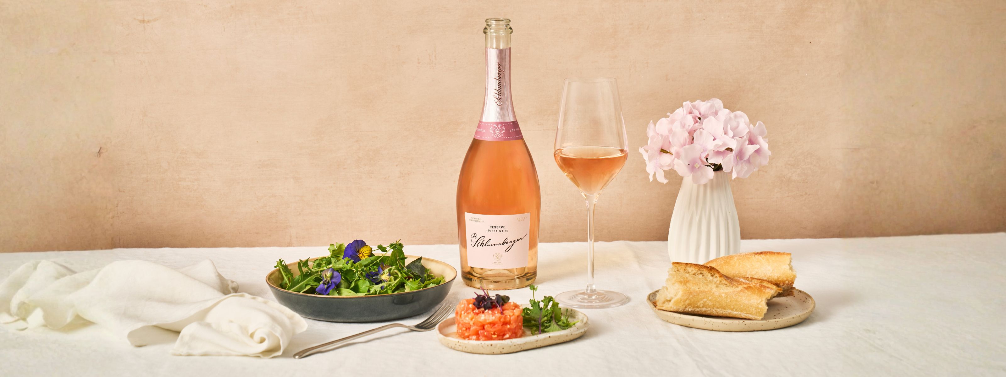 Eine Flasche Pinot Noir Reserev steht am Esstisch, sowie eine Salatschüssel und Lachstartar