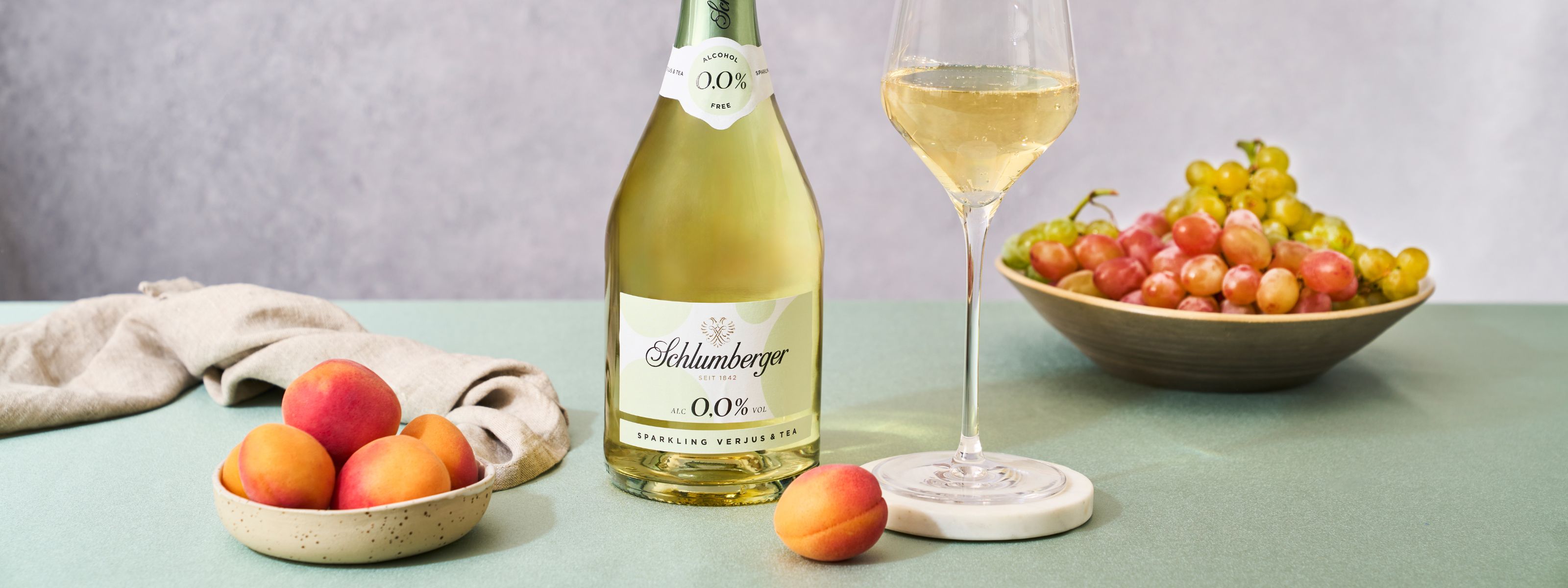 Eine Flasche Sparkling Verjus mit einem Glas und Marillen