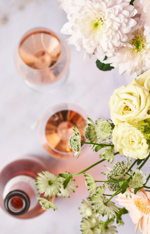 Schlumberger ROse ist in zwei Gläsern eingeschenkt und steht mit Blumen am Tisch
