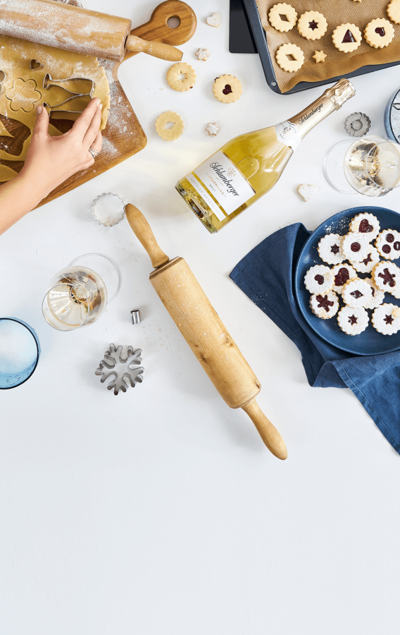 Gruppe beim gemeinsamen Kekse backen mit einer Flasche Schlumberger Sparkling Brut Klassik