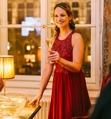 Dame im rotem Kleid erwartet mit Sektglas in der Hand Besuch