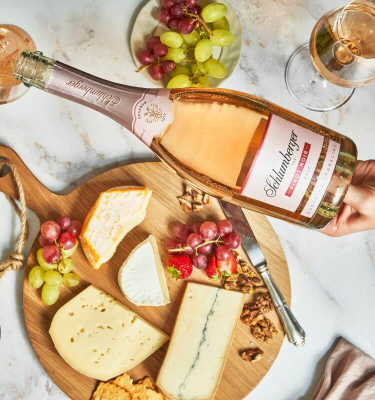 Pinot Noir Reserve wird eingeschenkt, daneben seht eine Käseplatte und Trauben