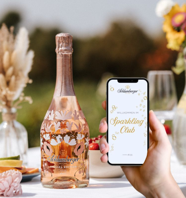 Spring Edition steht auf einem Tisch im freien, Person hat ein Smartphone in der Hand