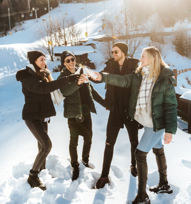 Vier Freunde stoßen im Schnee mit Ice Secco Sekt an
