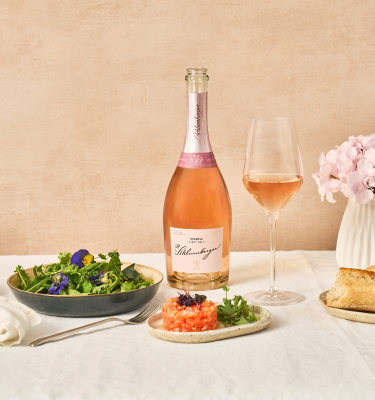 Eine Flasche Pinot Noir Reserev steht am Esstisch, sowie eine Salatschüssel und Lachstartar