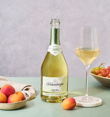 Sparkling Verjus steht mit eingeschenktem Glas und Marillen am Tisch