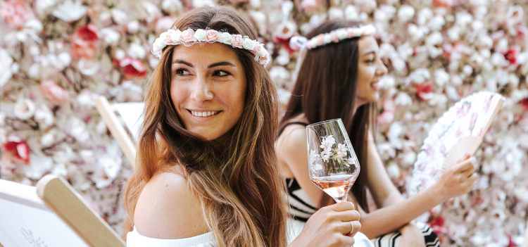 Frau mit Blumen im Hintergrund und einem Glas Schlumberger Sparkling Brut Spring Edition