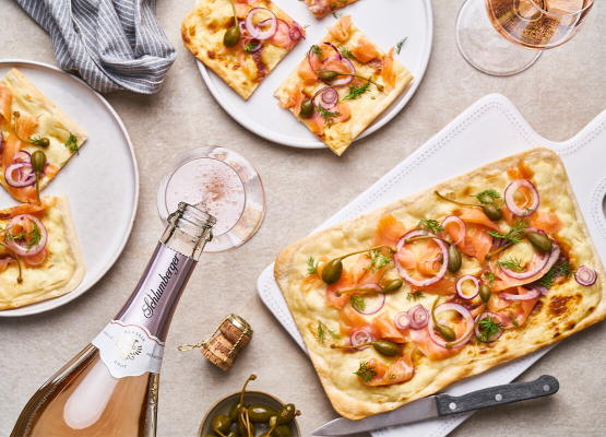 Schlumberger Rosé Brut wird in Gläser gefüllt, Flatbread mit Lachs steht am TIsch