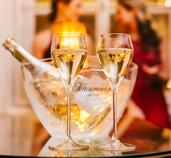 zwei Sekttuplen und kein Sektkühler mit Flasche stehen auf einem Tisch