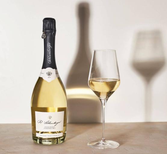 Schlumberger Chardonnay gr Resrve mit eingeschenktem Glas auf Tisch und Schlagschatten
