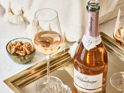 Schlumberger Rose steht am Tablett mit einem Glas und einer Schale voll Nüsse