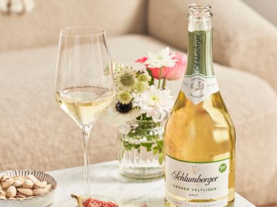 eine offene Flasche Schlumberger Grüener Veltliner steht mit einem Glas auf einem Couchtisch