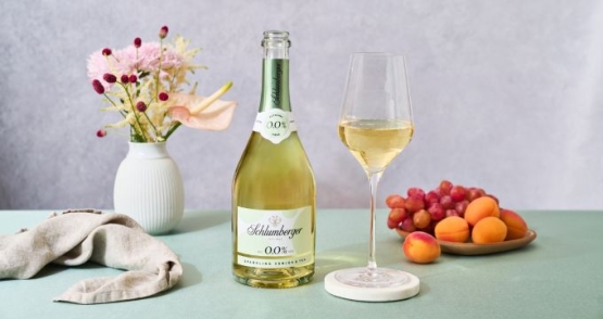Sparklinf Verjus steht mit Glas, Blumen und Marillen am Tisch